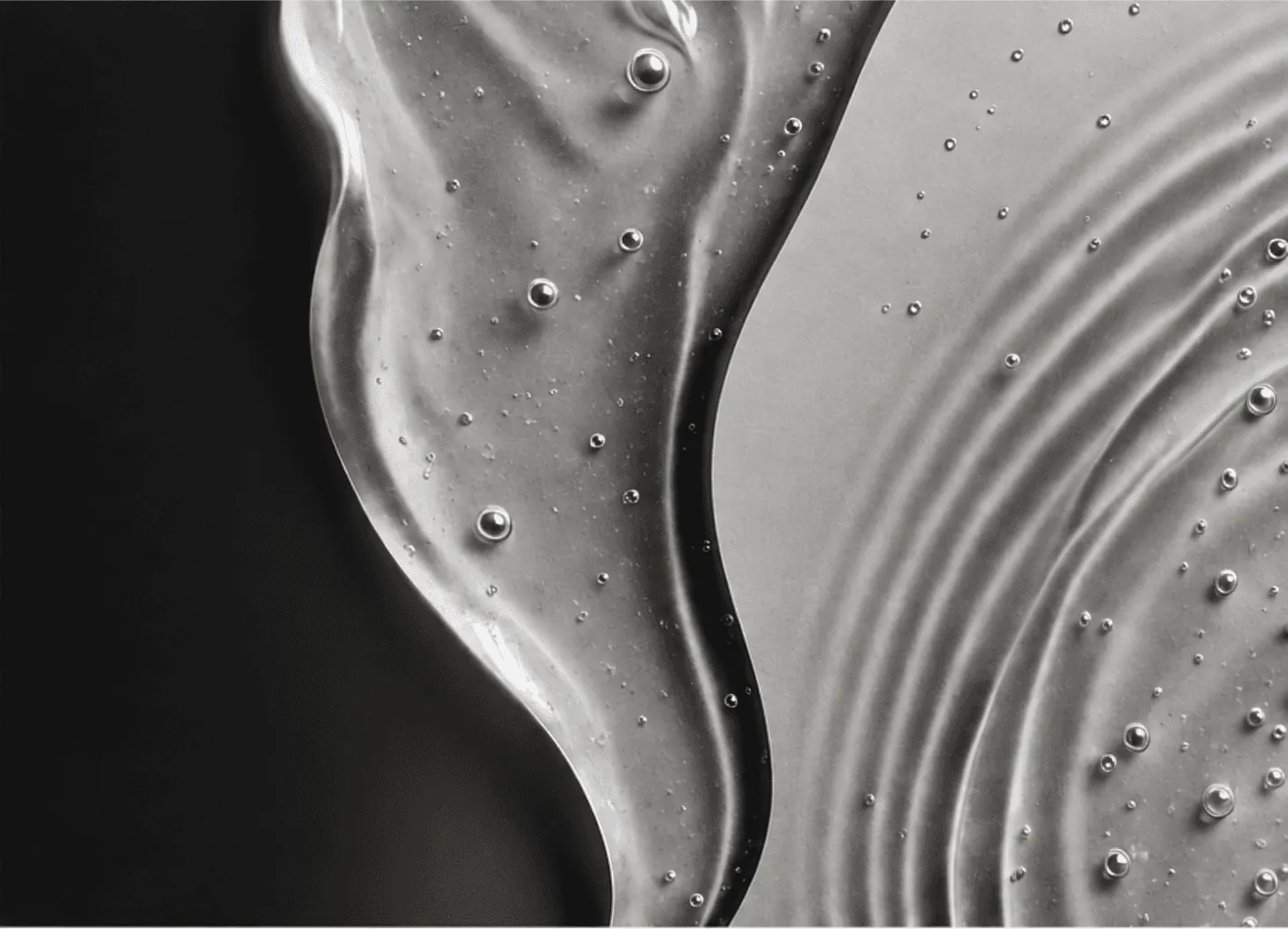 Monochrome close-up of translucent skincare gel with small bubbles